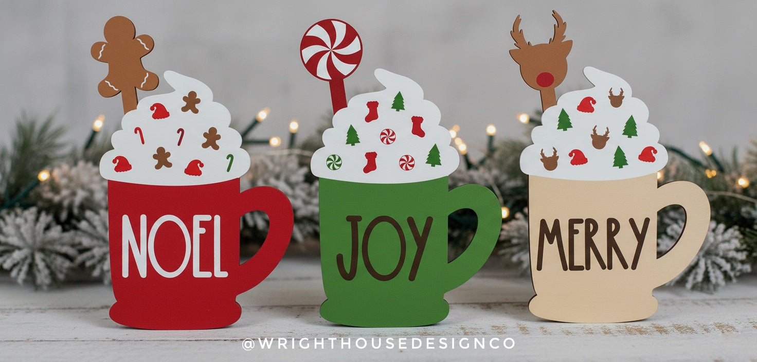 Decorative wooden hot chocolate mugs with 'NOEL', 'JOY', and 'MERRY' text, featuring gingerbread man, candy cane, and reindeer decorations for tiered trays